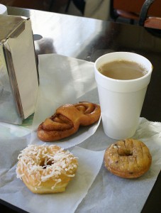 Styrofoam cup with coffee and two doughnuts