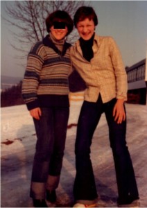 two teens standing in the snow in front of a building