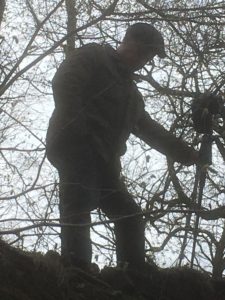 man sets up camera in woods