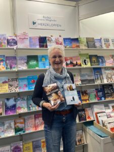 Frau mit zwei Romanen vor einem Bücherregal